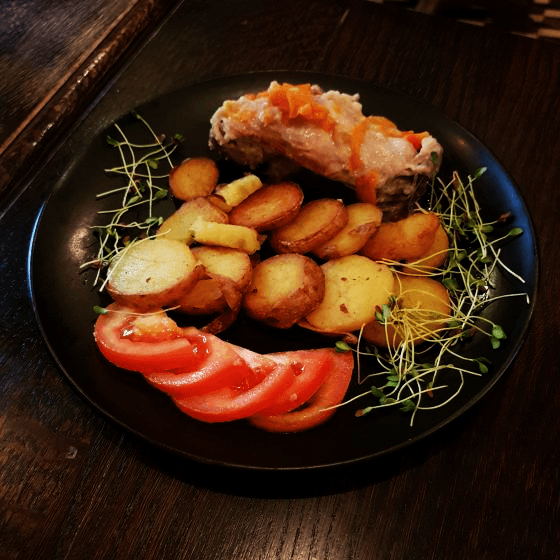 a plate of duck, potatoes, tomatoes and cress in a lviv galician restaurant